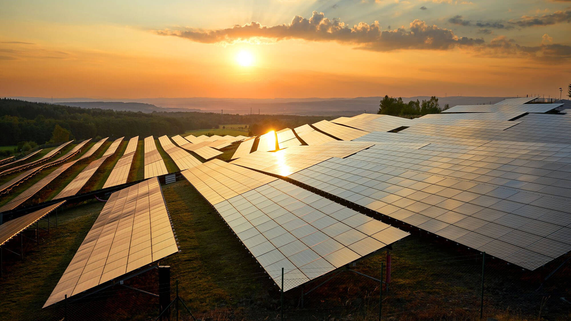 Photovoltaic panels of solar power station in the landscape at sunset. View from above.